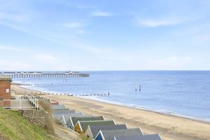 a beach with a pier and people in the water at Shiny Pebble in Southwold