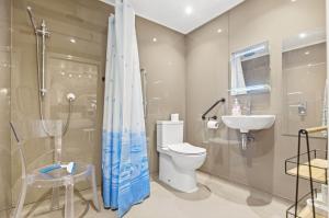 a bathroom with a shower and a toilet and a sink at Shiny Pebble in Southwold +3 photos