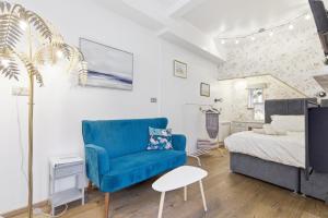 a living room with a blue chair and a bed at Shiny Pebble in Southwold