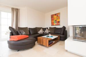 a living room with a black leather couch and a tv at Haus-Meerblick in Rantum