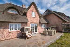 a brick house with a patio with a table and chairs at Haus-Meerblick in Rantum