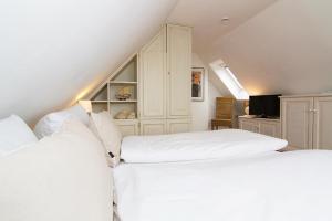 ein Schlafzimmer mit zwei weißen Betten und einem Fernseher in der Unterkunft Haus Seemöwe in Archsum