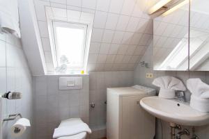 ein weißes Badezimmer mit Waschbecken und Fenster in der Unterkunft Haus Seemöwe in Archsum + 10 Fotos