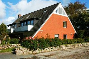 ein großes rotes Backsteinhaus mit schwarzem Dach in der Unterkunft Haus Seemöwe in Archsum
