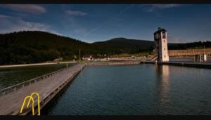 a bridge over a body of water with a clock tower at Apartament u Piotrusia i Paulinki in Stronie Śląskie