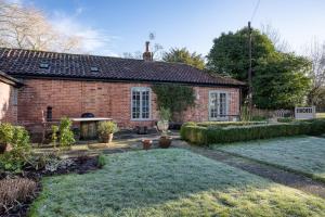 a brick house with a garden in front of it at The Cottage in Steeple Bumpstead