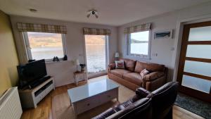 a living room with a couch and a tv and two windows at Sea Drift Self Catering in Dunan