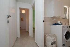 a laundry room with a washing machine and a hallway at Finalpia suite con box auto e deposito bici in Finale Ligure