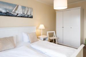 a bedroom with a bed and a painting of sailboats at Norderhoog-Whg-45-2-OG-O-Wohnung-45 in Westerland +7 photos