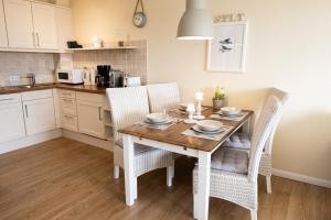 a kitchen with a wooden table with chairs and a dining room at Norderhoog-Whg-45-2-OG-O-Wohnung-45 in Westerland
