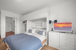 a white bedroom with a bed and a flat screen tv at Norderhoog-Whg-33-1-OG-O-Wohnung-33 in Westerland