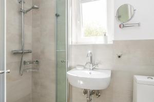 a bathroom with a sink and a shower with a mirror at Bandomir-Bungalow-Wohnung-02 in Westerland