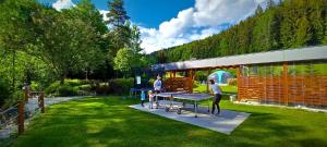 two people standing around a ping pong table in a yard at Spa & Pool VILA ANNA in Halenkov