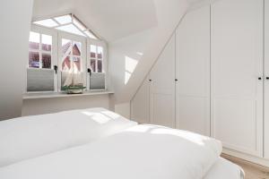a white bedroom with a bed and a window at Haus-Friesenperle in Westerland