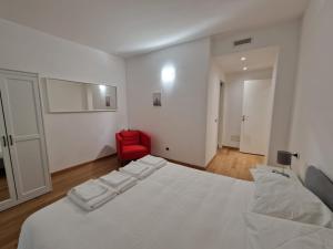 a bedroom with a white bed and a red chair at Il Rifugio di Boccadasse in Genoa
