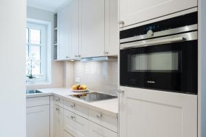 a kitchen with white cabinets and a black microwave at Stadtrose in Westerland