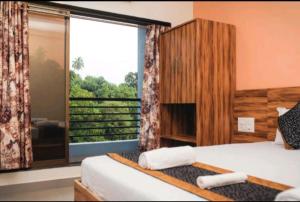 a bedroom with two beds and a large window at Lotus Beach Resort in Nagaon