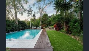 a swimming pool in a yard with grass and trees at The Hideaway Boutique Guest House in Jindalee