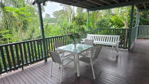 a table and chairs on a deck with a bench at The Hideaway Boutique Guest House in Jindalee