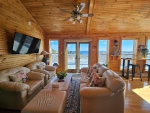 a living room with leather couches and a flat screen tv at Panoramic Sunrise House in Terence Bay