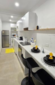 a kitchen with white cabinets and a counter with black chairs at The Hideaway Boutique Guest House in Jindalee