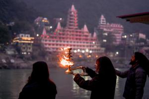 a group of three women holding a lit candle at Hotel Ishan - A Ganges Riverside Retreat by Salvus in Rishīkesh