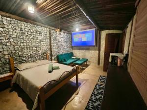 a bedroom with a bed and a flat screen tv at Chalé Medieval in Brumadinho