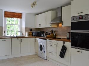 a kitchen with white cabinets and a washer and dryer at Orchard Cottage - Uk12525 in Garlieston