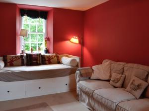 a living room with red walls and a couch and a window at Orchard Cottage - Uk12525 in Garlieston