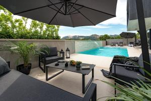 a patio with a pool and a table and an umbrella at Luxury Villa Black Cube with Heated pool in Mlini