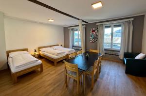 a room with two beds and a table and chairs at Downtown Apartments in Interlaken