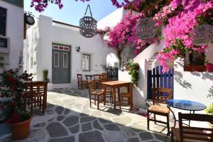 a patio with tables and chairs and pink flowers at Maison d'Elli in Mesochórion