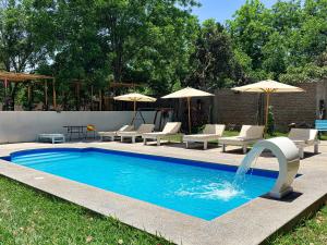 a pool with chairs and umbrellas in a yard at Serenity Lodge in Ica