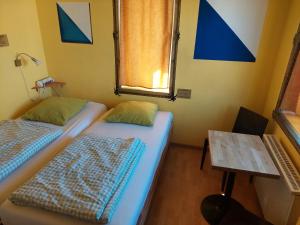 two beds in a room with a table and a window at Oldtown Hostel Otter in Zurich