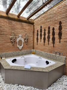 a bath tub in a room with a brick wall at Pousada Alto da Neblina in Monte Verde +64 photos