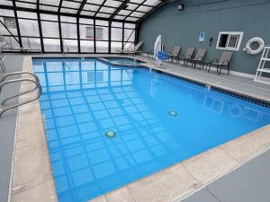 a large swimming pool with blue water in a building at Super 8 by Wyndham Logan in Logan