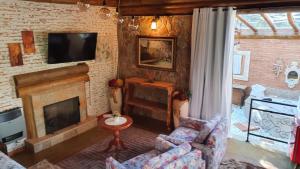 a living room with a fireplace and a tv at Pousada Alto da Neblina in Monte Verde