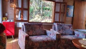 a living room with two chairs and a table at Pousada Alto da Neblina in Monte Verde