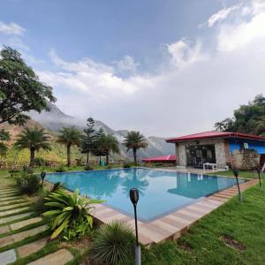 a swimming pool with a house and mountains in the background at Fun N Forest Resort in Dehradun