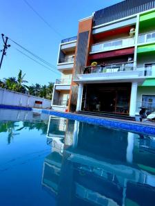 a hotel with a swimming pool in front of a building at Lotus Beach Resort in Nagaon +12 photos