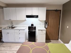 a kitchen with white cabinets and a black dishwasher at Super 8 by Wyndham Logan in Logan