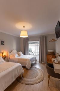 a hotel room with two beds and a television at O VIOLAS - Art Coffee & Guesthouse in Praia de Mira