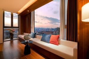 a living room with a couch and a large window at CICILIA Rouge Dalat in Da Lat