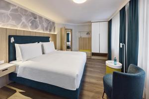 a hotel room with a bed and a chair at Dorint Parkhotel Jordanbad in Biberach an der Riß