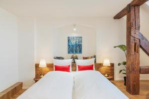 a bedroom with a large white bed with red pillows at Tailormade Hotel RÜDEN Schaffhausen in Schaffhausen +28 photos