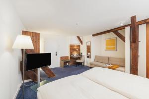 a bedroom with a bed and a living room at Tailormade Hotel RÜDEN Schaffhausen in Schaffhausen