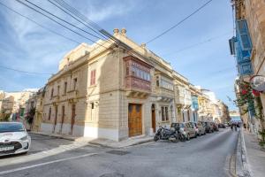 an old building on a city street with cars parked at NORFOLK Suites in Sliema
