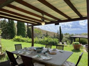 a gray table with chairs under a wooden pergola at Porto Ercole Prestige Villa in Cala Galera