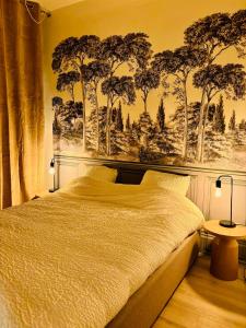 a bedroom with a bed with trees on the wall at La Scène Audomaroise - Appartement hyper centre in Saint-Omer +7 photos