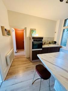 a kitchen with a counter and a table with a chair at La Scène Audomaroise - Appartement hyper centre in Saint-Omer